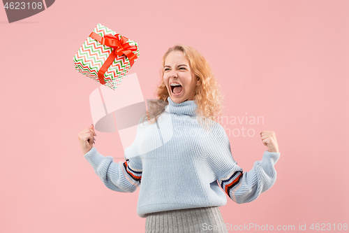 Image of Woman with big beautiful smile holding colorful gift box.