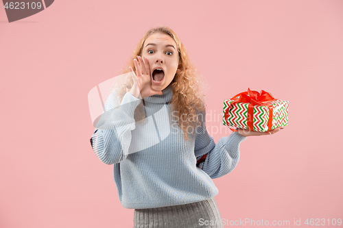 Image of Woman with big beautiful smile holding colorful gift box.