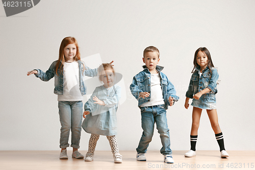 Image of The portrait of cute little boy and girls in stylish jeans clothes looking at camera at studio