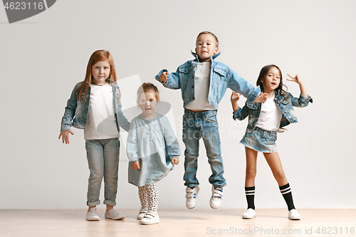 Image of The portrait of cute little boy and girls in stylish jeans clothes looking at camera at studio