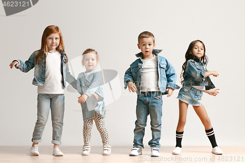 Image of The portrait of cute little boy and girls in stylish jeans clothes looking at camera at studio