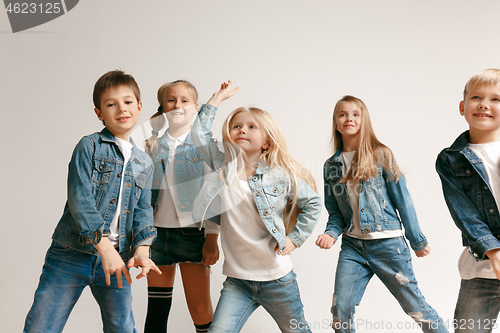 Image of The portrait of cute little boy and girls in stylish jeans clothes looking at camera at studio