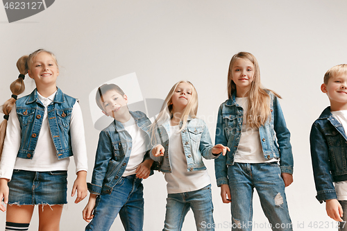 Image of The portrait of cute little boy and girls in stylish jeans clothes looking at camera at studio