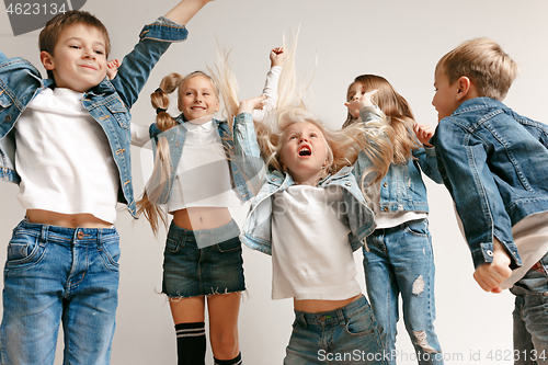 Image of The portrait of cute little boy and girls in stylish jeans clothes looking at camera at studio