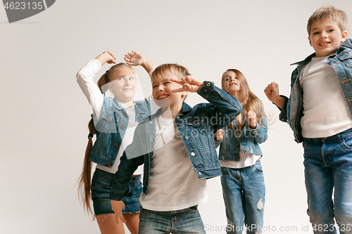 Image of The portrait of cute little boy and girls in stylish jeans clothes looking at camera at studio