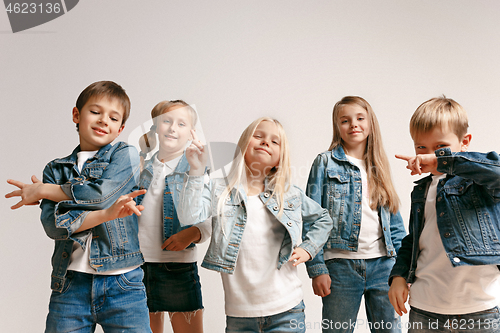 Image of The portrait of cute little boy and girls in stylish jeans clothes looking at camera at studio