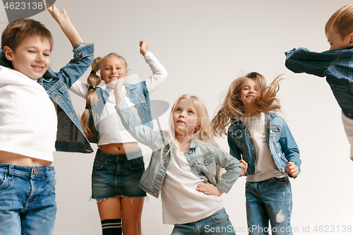 Image of The portrait of cute little boy and girls in stylish jeans clothes looking at camera at studio