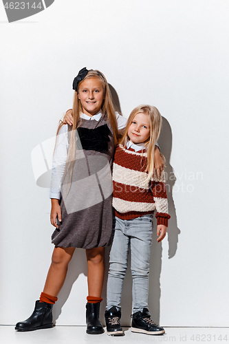 Image of The portrait of cute little girls in stylish jeans clothes looking at camera at studio