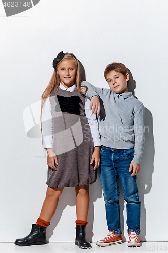 Image of The portrait of cute little boy and girl in stylish jeans clothes looking at camera at studio