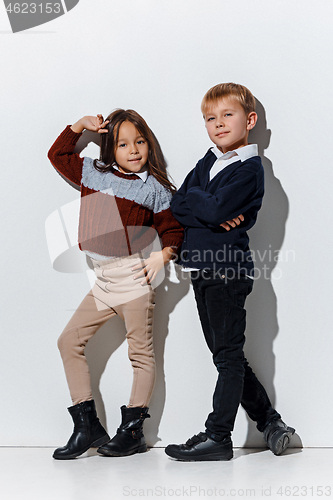 Image of The portrait of cute little boy and girl in stylish jeans clothes looking at camera at studio