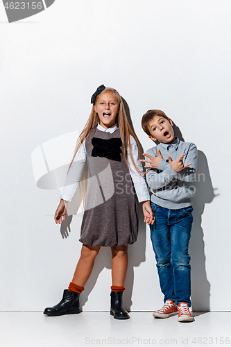 Image of The portrait of cute little boy and girl in stylish jeans clothes looking at camera at studio