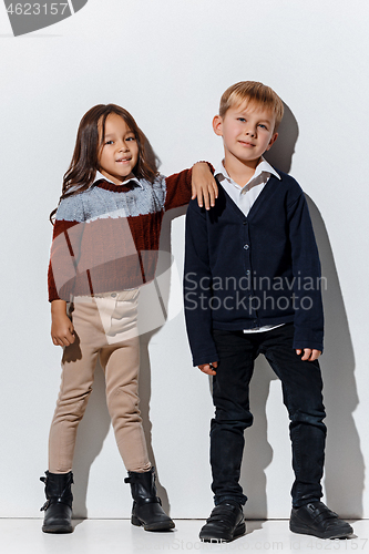 Image of The portrait of cute little boy and girl in stylish jeans clothes looking at camera at studio