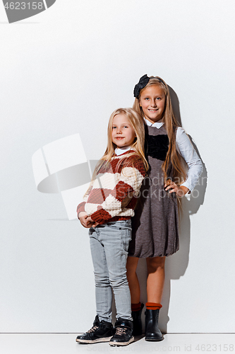 Image of The portrait of cute little girls in stylish jeans clothes looking at camera at studio