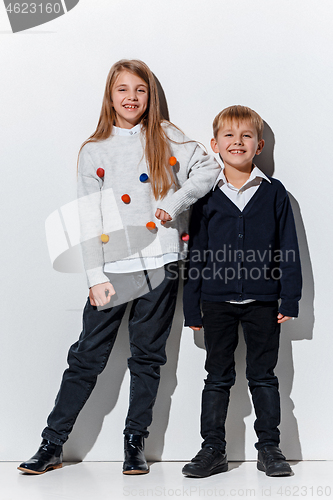 Image of The portrait of cute little boy and girl in stylish jeans clothes looking at camera at studio