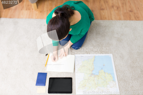Image of woman with notebook and travel map at home