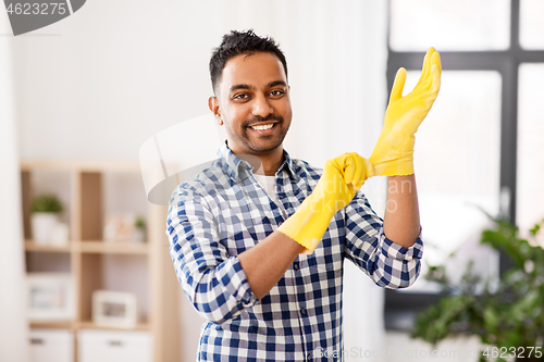 Image of indian man putting protective rubber gloves on