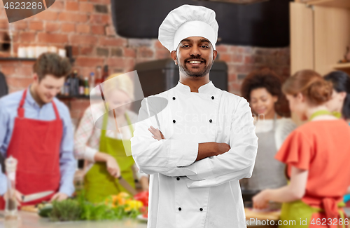 Image of happy male indian chef in toque at cooking class