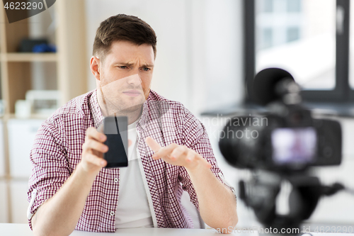 Image of male vlogger with smartphone videoblogging at home