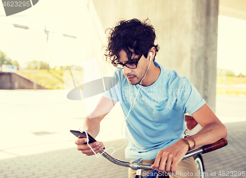 Image of man with smartphone and earphones on bicycle