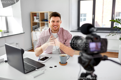 Image of male blogger with camera videoblogging at home