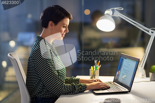 Image of businesswoman working on laptop at night office