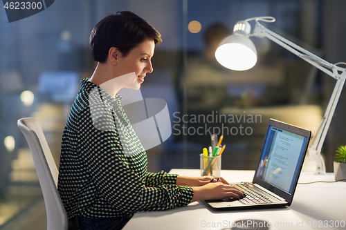 Image of businesswoman working on laptop at night office