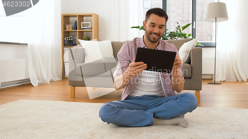 Image of smiling man using tablet computer at home