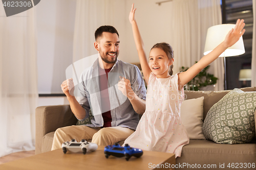 Image of father and daughter playing video game at home