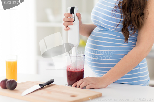 Image of pregnant woman with blender making smoothie drink