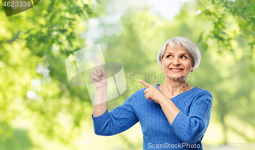 Image of smiling senior woman pointing fingers to something