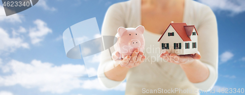 Image of close up of woman with house model and piggy bank