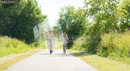 Image of happy young couple riding bicycles in summer