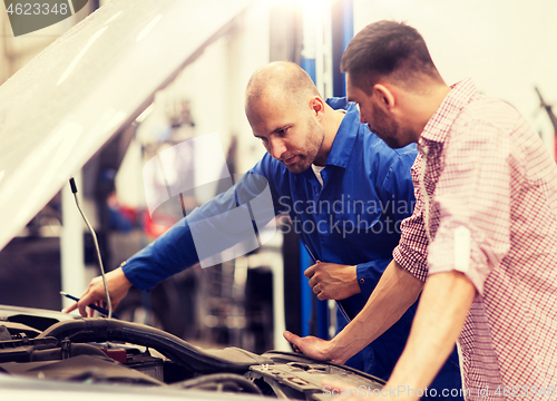 Image of auto mechanic with clipboard and man at car shop