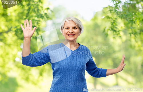 Image of smiling senior woman touching something imaginary