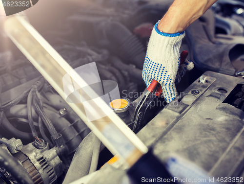 Image of mechanic man with pliers repairing car at workshop