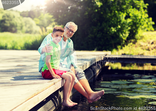 Image of grandfather and grandson sitting on river berth