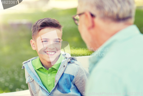 Image of grandfather and grandson talking at summer park