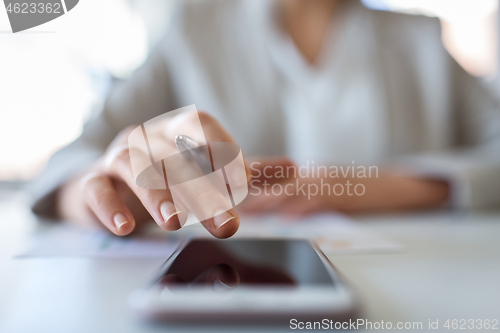 Image of hand of businesswoman using smartphone at office