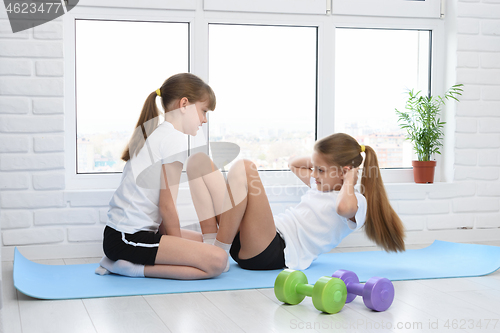 Image of Girl helps another girl to do exercise for the abs