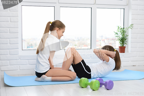 Image of Sisters perform sports exercises at home in self-isolation mode