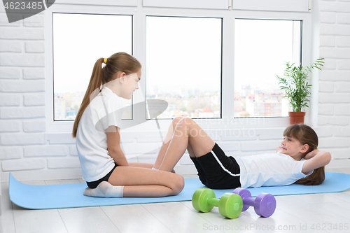 Image of Sisters do sports exercises at home in self-isolation mode