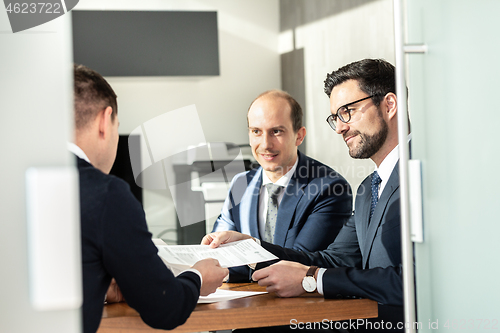 Image of Group of confident successful business people reviewing and signing a contract to seal the deal at business meeting in modern corporate office.