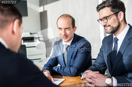 Image of Team of confident successful business people discussing the contract terms at business meeting in modern corporate office.