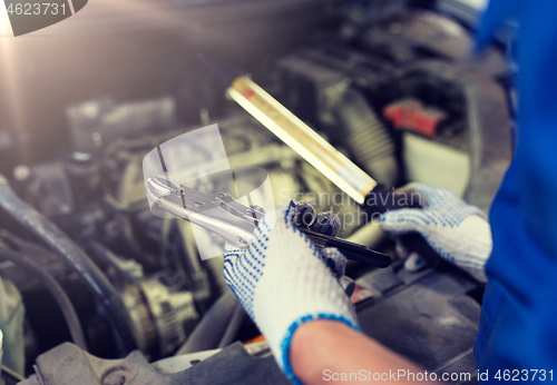 Image of mechanic man with pliers repairing car at workshop