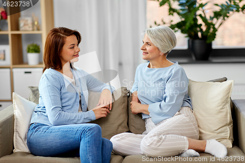 Image of senior mother talking to adult daughter at home