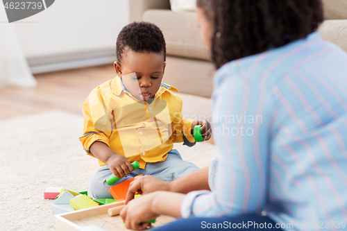 Image of mother and baby playing with toy blocks at home