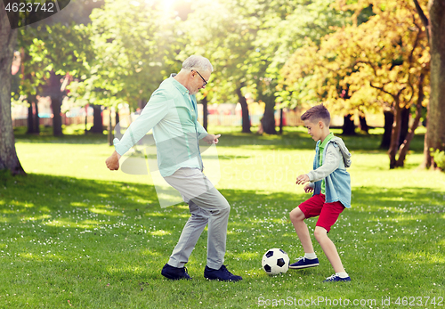 Image of old man and boy playing football at summer park