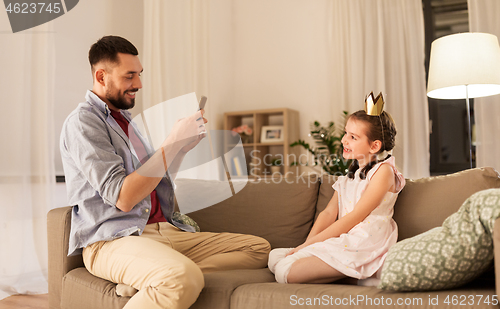 Image of father photographing daughter by cellphone at home