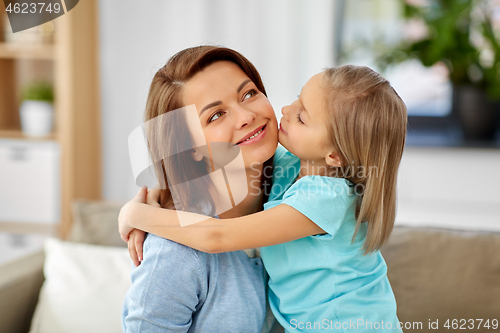 Image of little daughter hugging her mother on sofa at home