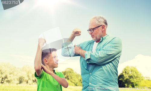 Image of happy grandfather and grandson showing muscles